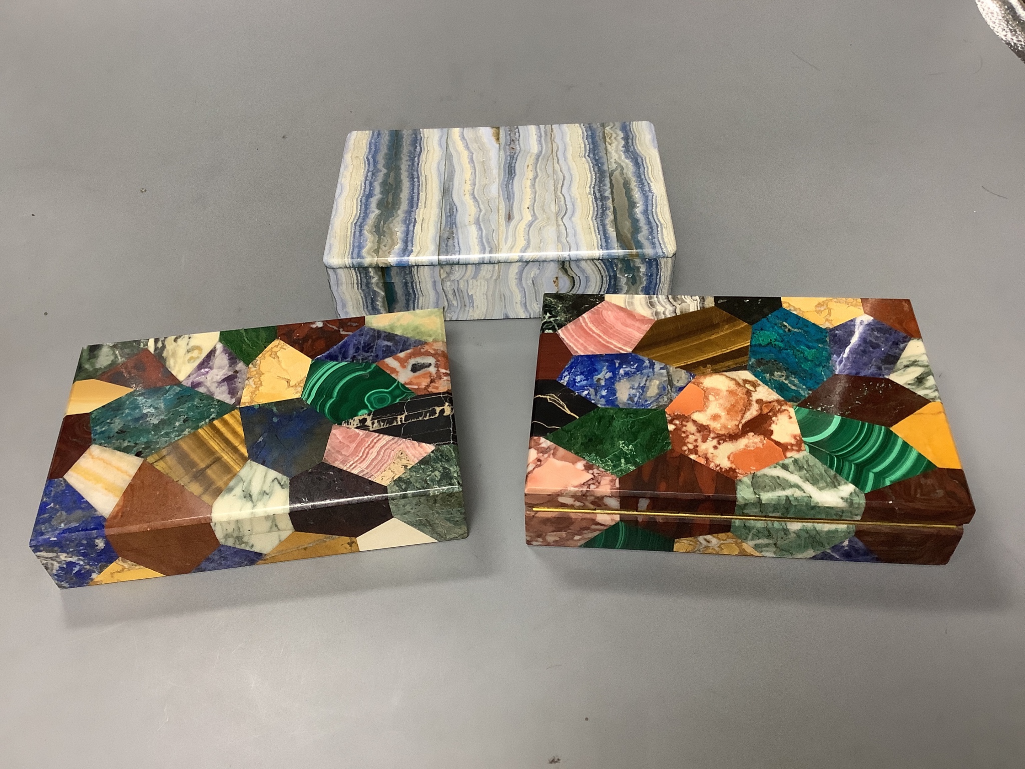 Two specimen marble cigarette boxes, 15cm and a similar blue agate cigarette box, 15.5cm, all three retailed by Asprey London and signed to the hinge mount